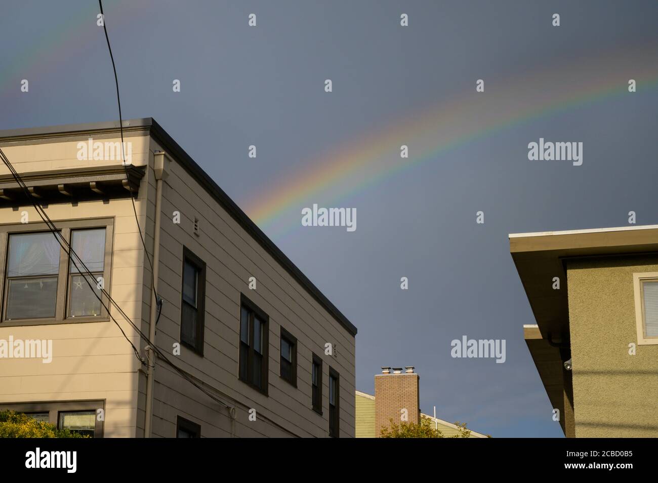 Rainbow Over Apartment Building and Blue Sky in The City Stock Photo