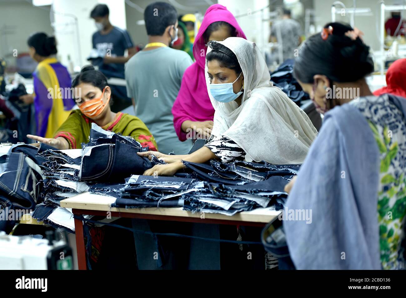 Dhaka. 12th Aug, 2020. People work at a garment factory in Dhaka, Bangladesh, on Aug. 12, 2020. Bangladesh's July export income was over 44 percent higher than that in June, meaning the country's export sector is limping back to normalcy after suffering serious blows owing to COVID-19 impacts. Of the total earnings, the Export Promotion Bureau (EPB) data showed the country's income from ready-made garment items, including knitwear and woven, stood at 3.24 billion U.S. dollars. Credit: Xinhua/Alamy Live News Stock Photo