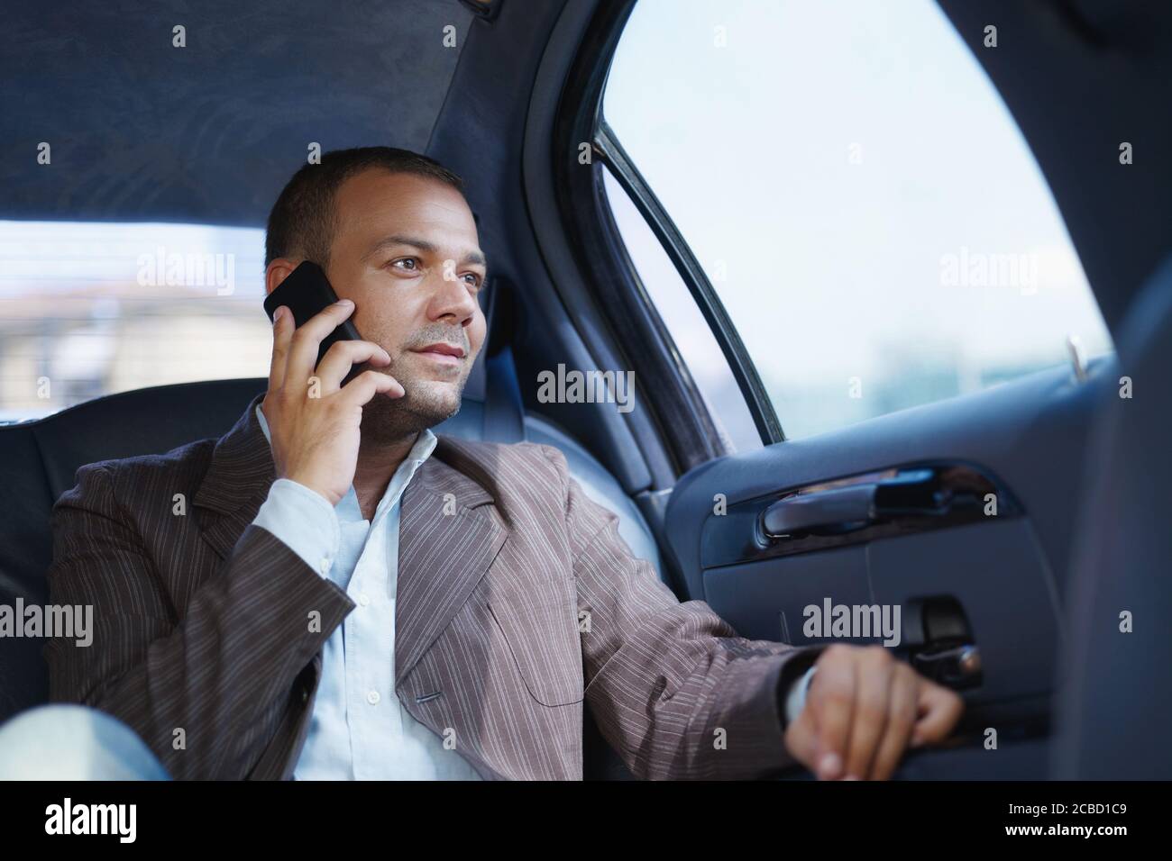 Businessman Talking On Mobile Phone Travelling In Limousine Stock Photo