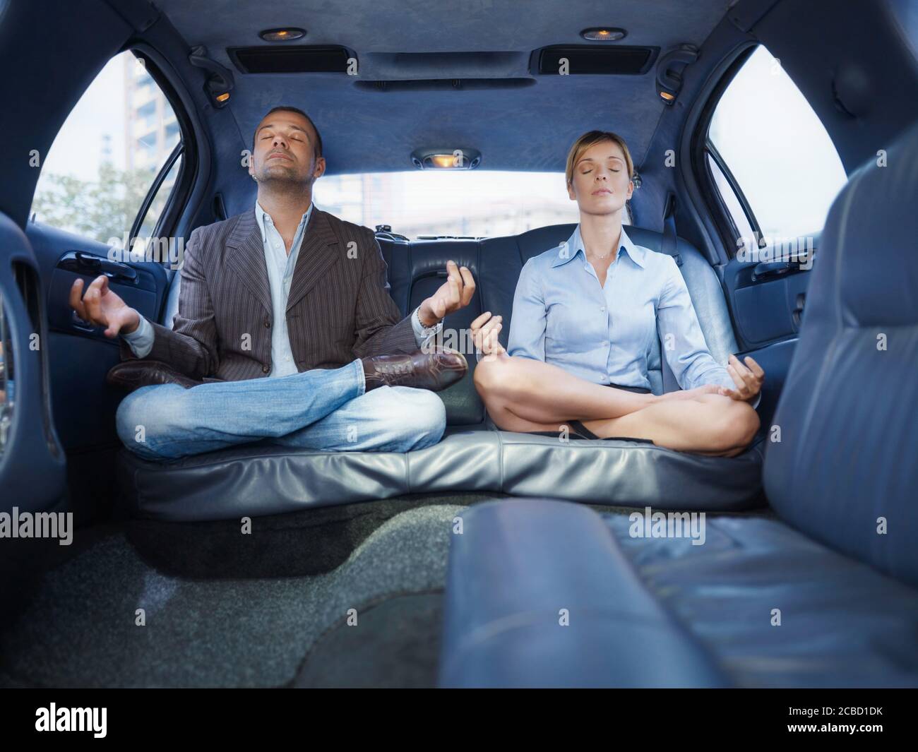 Businessman And Assistant Doing Yoga Sitting In Limousine Car Stock Photo