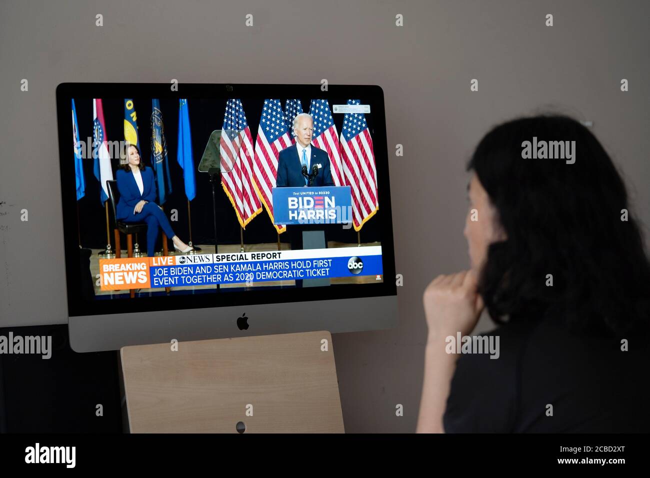 (200812) -- ARLINGTON (U.S.), Aug. 12, 2020 (Xinhua) -- A woman at a house in Arlington, Virginia, watches news showing U.S. presumptive Democratic presidential nominee Joe Biden (R, on the screen) speaking at a campaign event together with Kamala Harris in Wilmington, Delaware, the United States, on Aug. 12, 2020. U.S. presumptive Democratic presidential nominee Joe Biden attended Wednesday a campaign event in his hometown of Wilmington, together with Kamala Harris, his choice of Democratic vice presidential candidate, in what was the duo's first public appearance as running mates. (Xinhua/Li Stock Photo