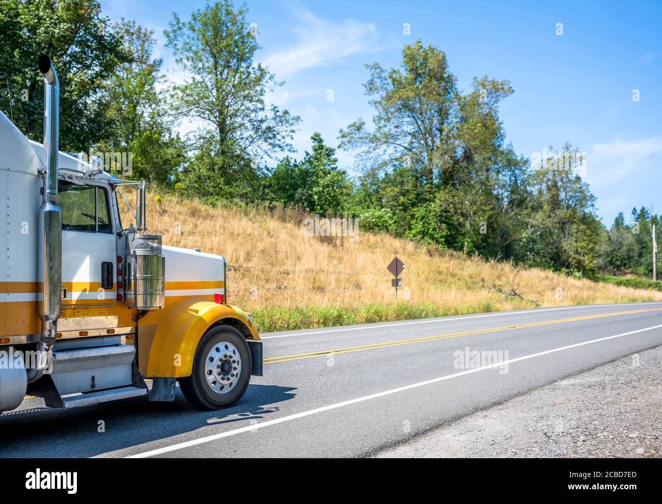 Two tone white and yellow bonnet classic big rig industrial diesel semi  truck tractor with vertical chrome pipes climbing on the road between the  hill Stock Photo - Alamy