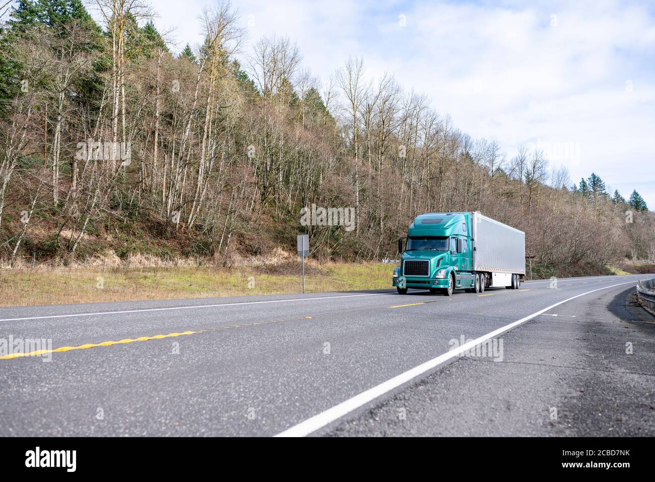 Loaded industrial green big rig semi truck transporting frozen commercial cargo in shine stainless steel refrigerator semi trailer running on the safe Stock Photo