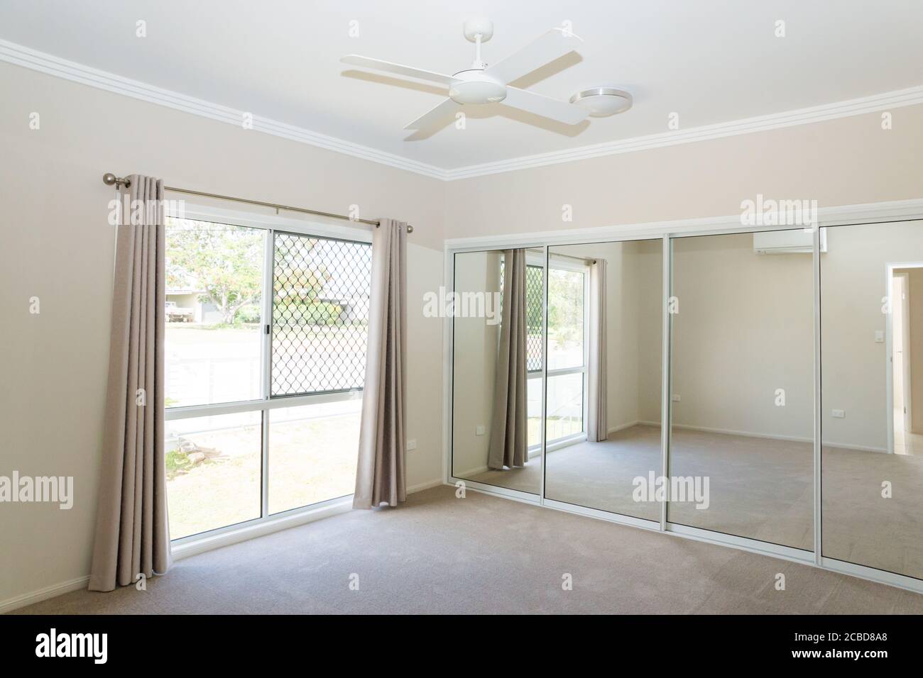 Bedroom in new contemporary house with sliding glass mirror doors and sliding glass windows with security screens Stock Photo