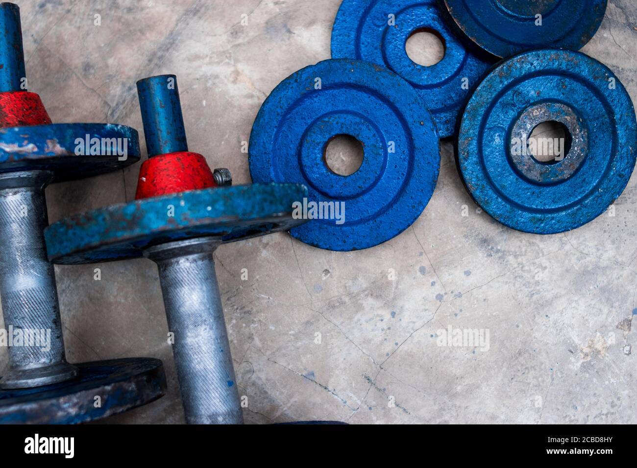 Old blue gym weights on the floor in a gym Stock Photo