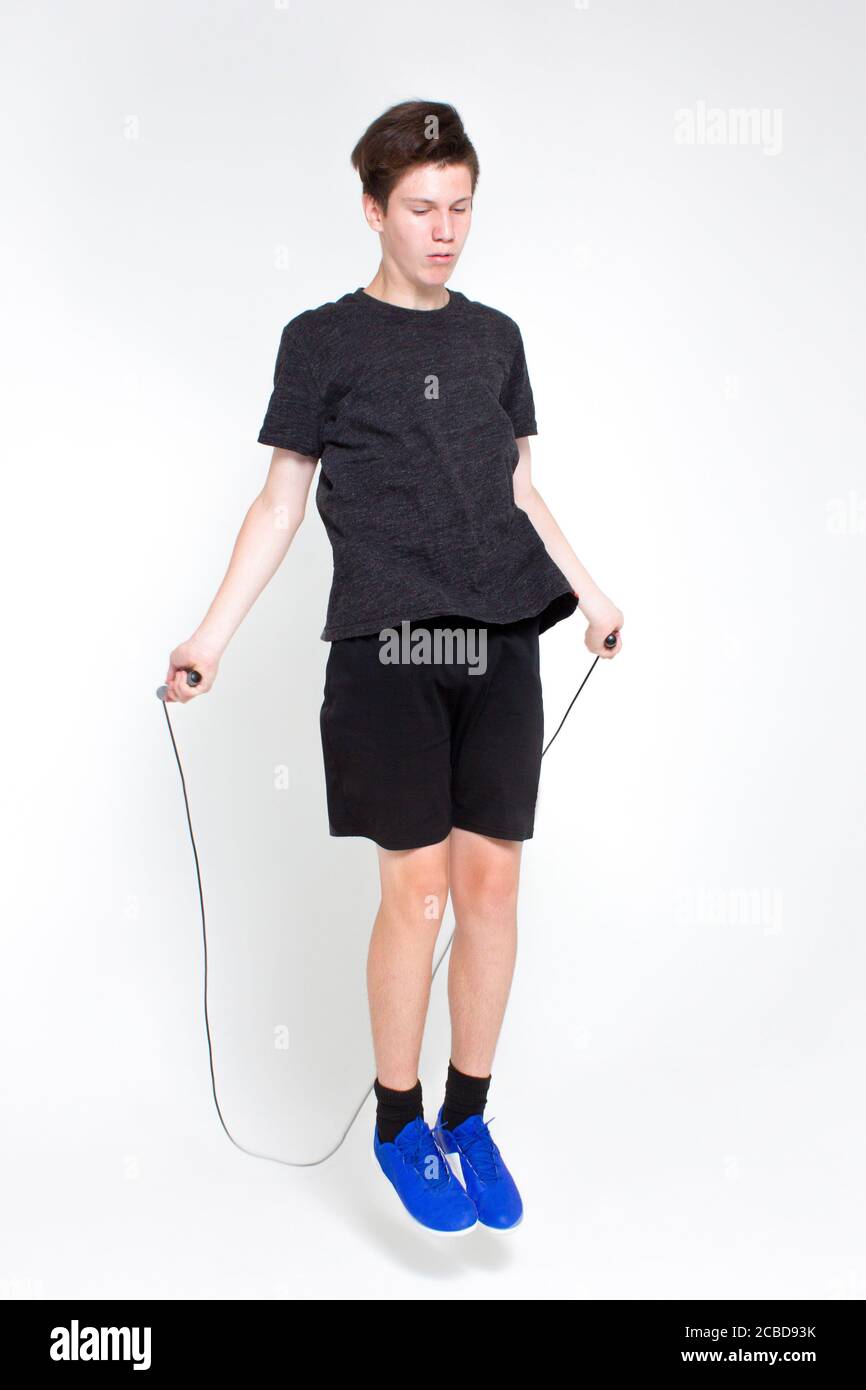 A Young Man In A Black Sports T Shirt And Shorts Blue Sneakers Practicing Jumping Rope Isolated On White Stock Photo Alamy