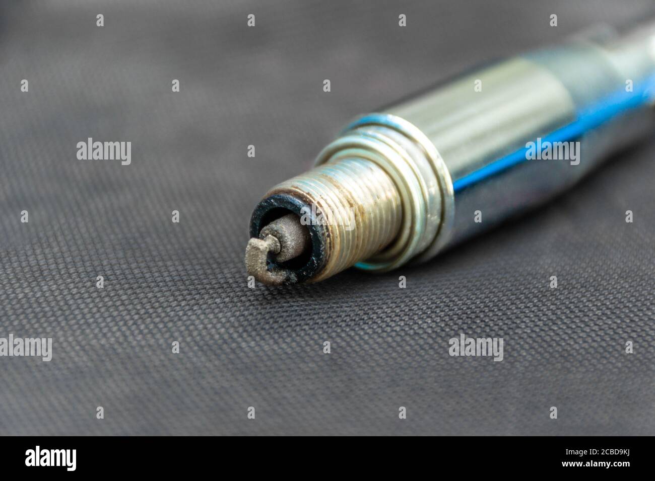 spark plug with carbon deposits is unscrewed and is in the key, electrode close-up, selective focus Stock Photo