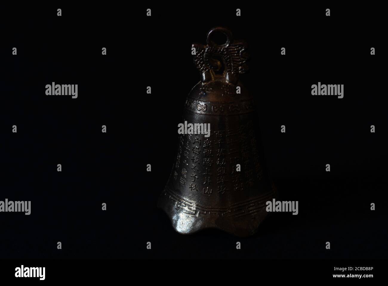 antique thai bronze bell with inscription on black background Stock Photo