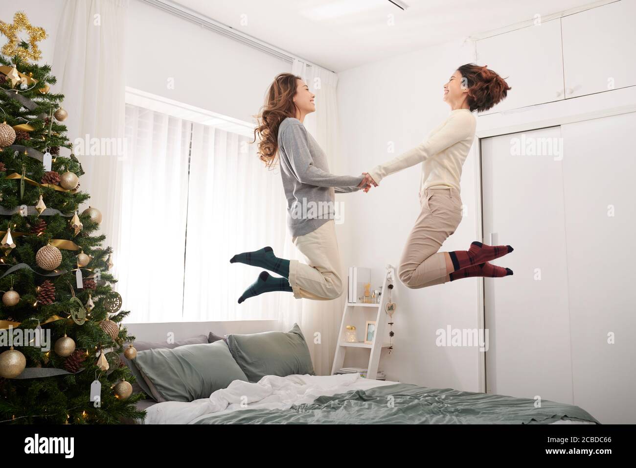 Happy kids jumping, having fun, playing on bed in bedroom enjoying of morning Stock Photo