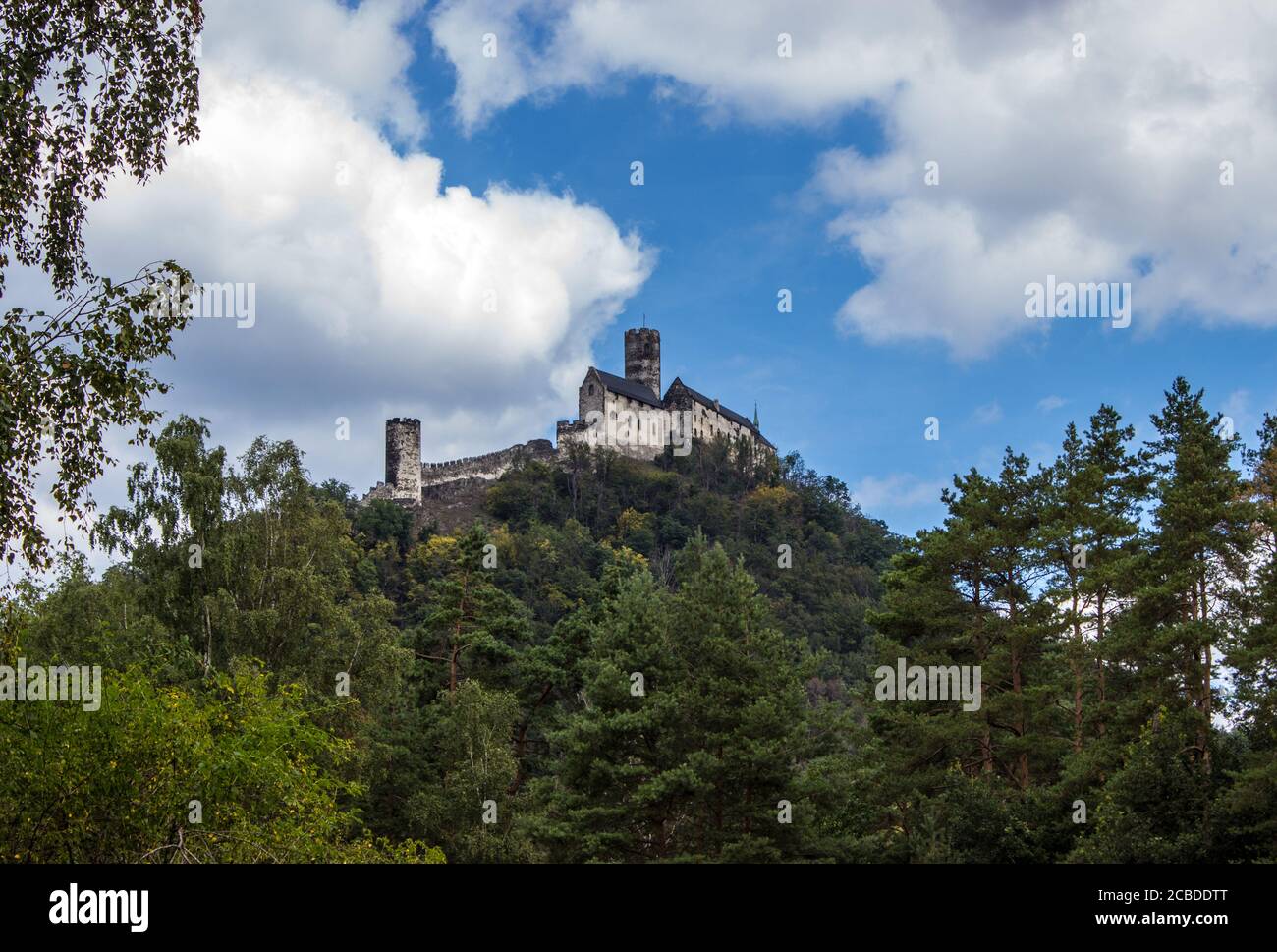 Panoramic view of Bezdez castle in the Czech Republic. In the foreground there are trees, in the background is a hill with castle and there are a whit Stock Photo