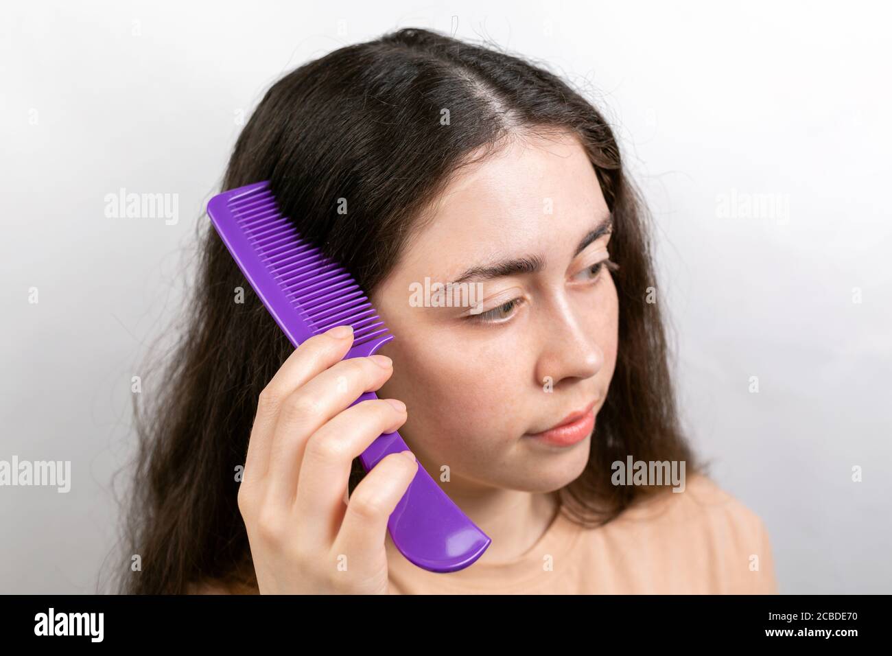 The woman is a parting her hair with a comb and showing the