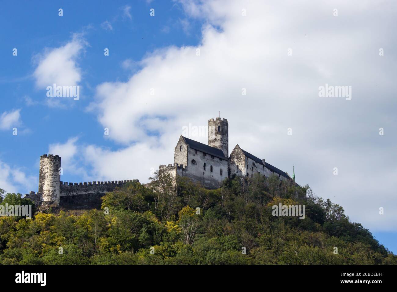 Panoramic view of Bezdez castle with two towers in the Czech Republic. In the foreground there are trees, in the background is a hill with castle and Stock Photo