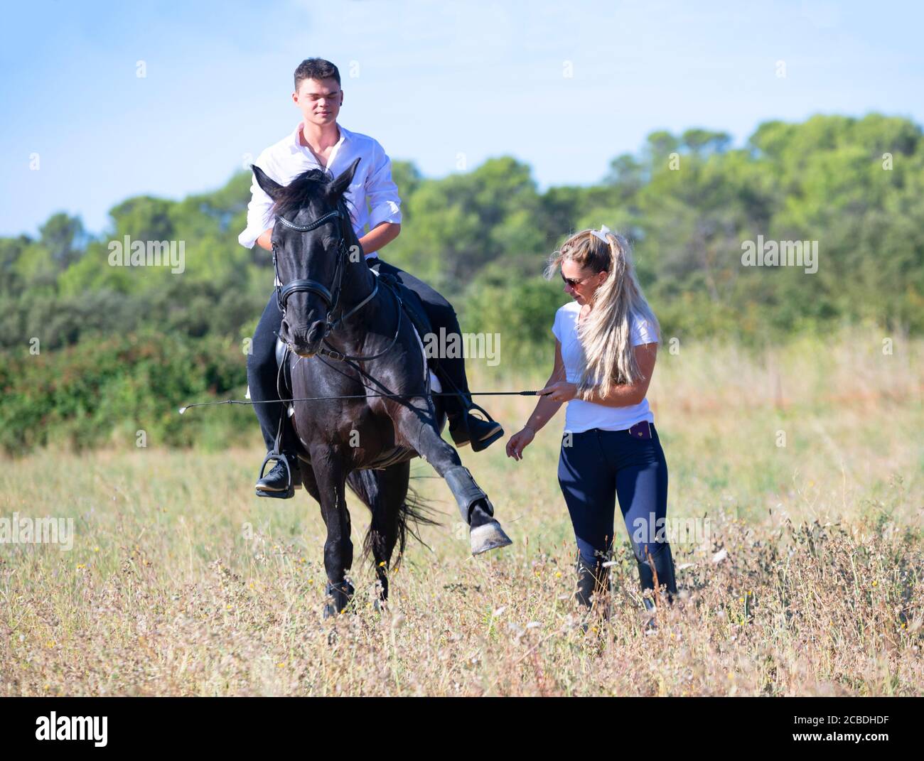 riding teenager are training her black horse with teacher Stock Photo