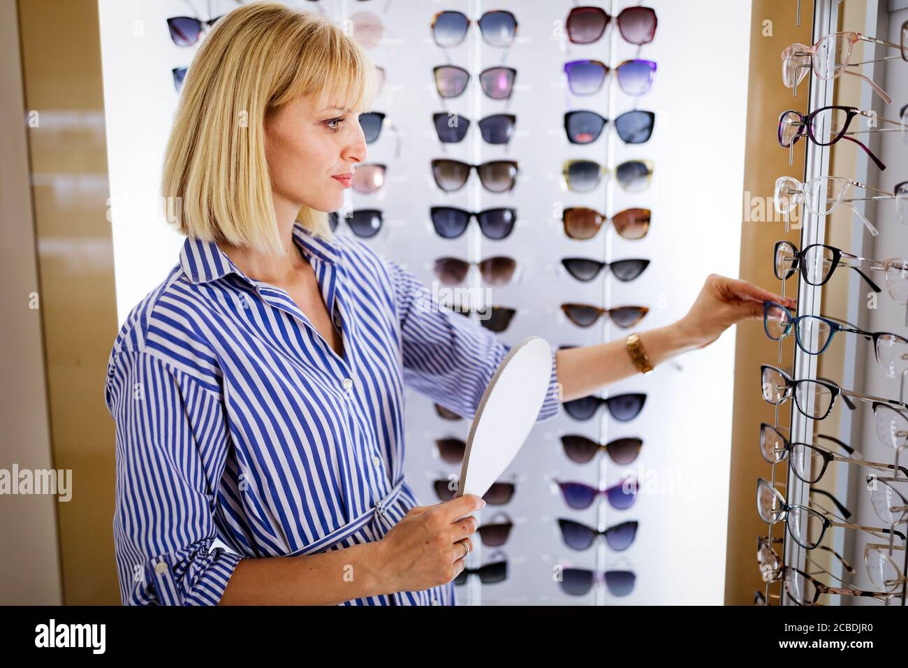 Health care, eyesight and vision concept. Happy woman choosing glasses