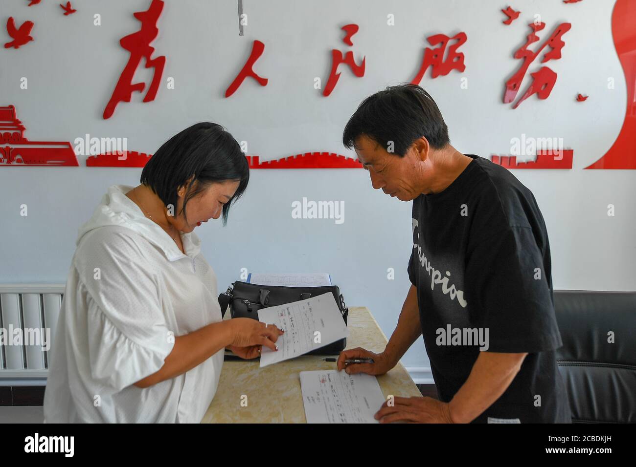 Zhenlai, China's Jilin Province. 12th Aug, 2020. A goverment staff member offers service to villager Bao Chunmiao (L) in Chatai Village, Heiyupao Township, Zhenlai County, northeast China's Jilin Province, Aug. 12, 2020. Once a national-level poverty-stricken county, Zhenlai County has shaken off poverty in 2019 after years of anti-poverty efforts. Now the county plans to upgrade its rural infrastructure and industrial structure with various supportive funds. Credit: Zhang Nan/Xinhua/Alamy Live News Stock Photo