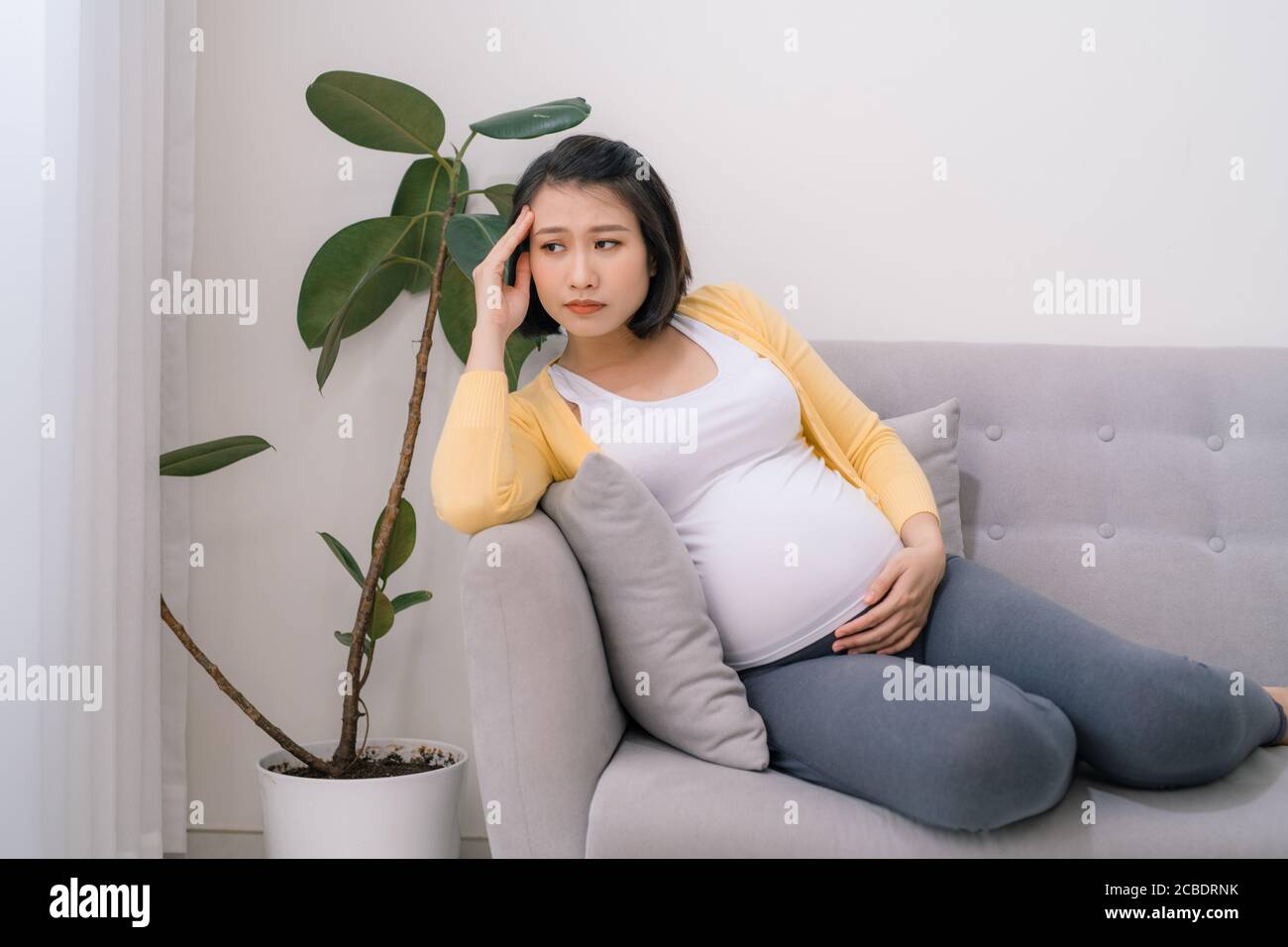 Young expectant, pregnant woman with headache copy space. Stock Photo