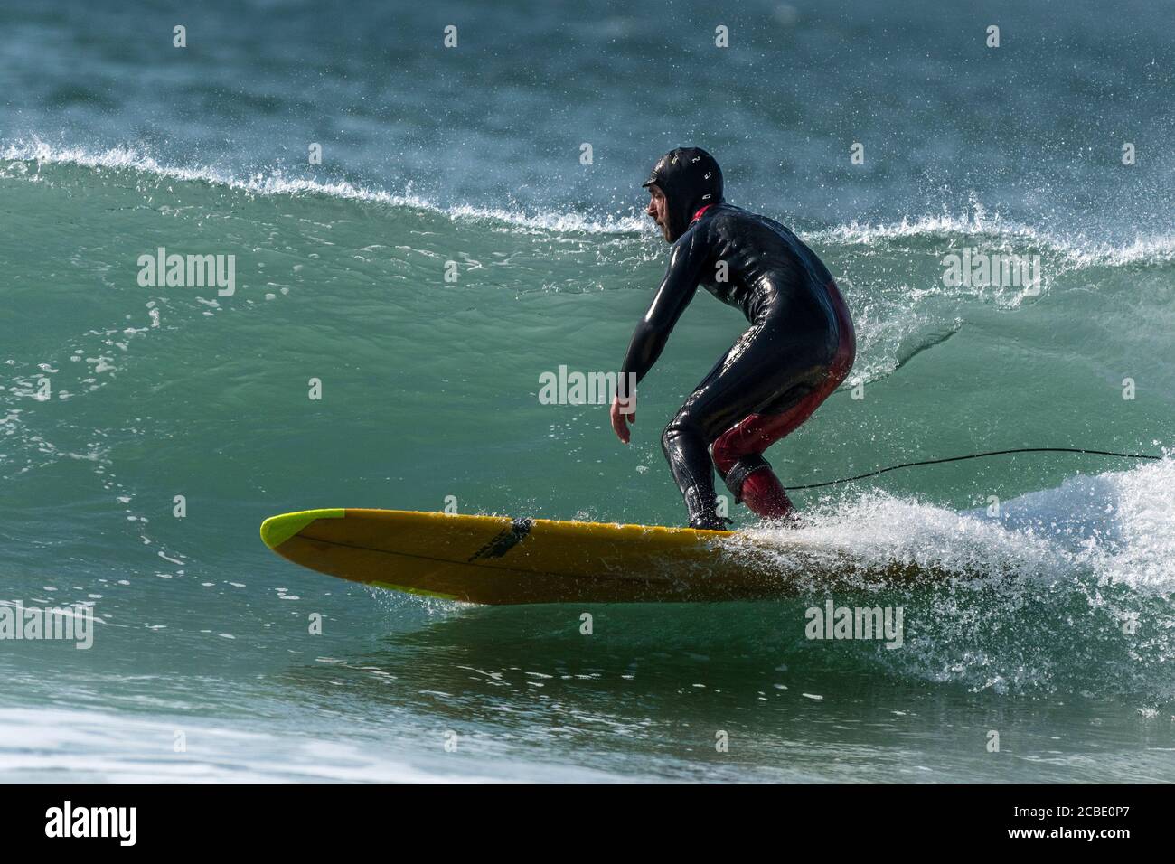 A surfer using a longboard surfing at Fistral in Newquay in Cornwall