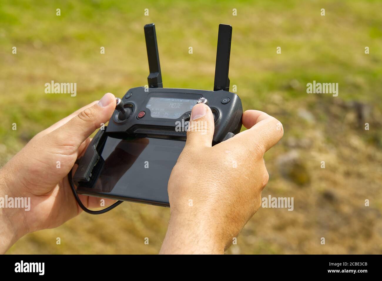 Man using remote control to operating drone assign blurred land. Stock Photo