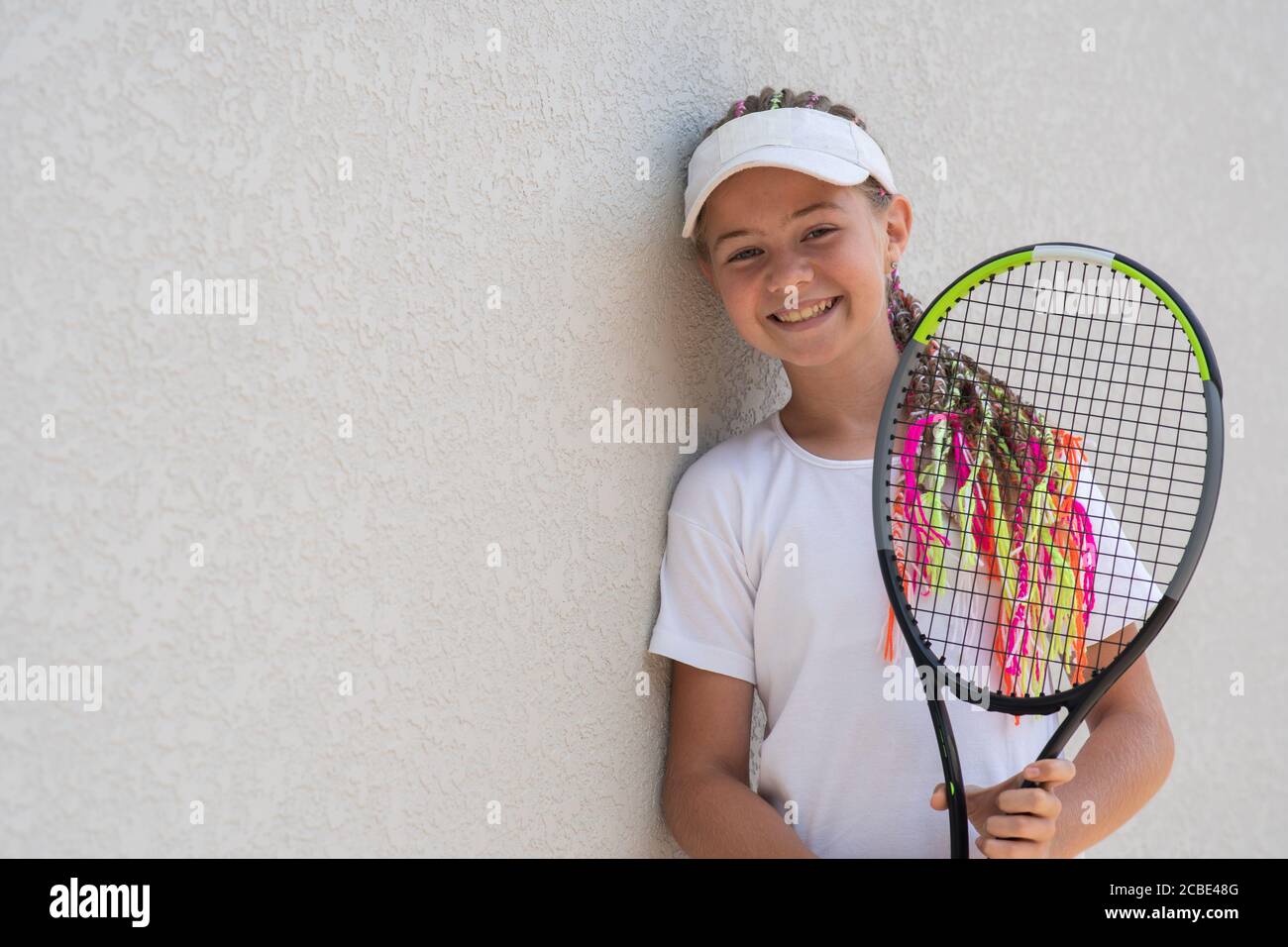 Beginner smiling girl tennis player with a tennis racket in her hands