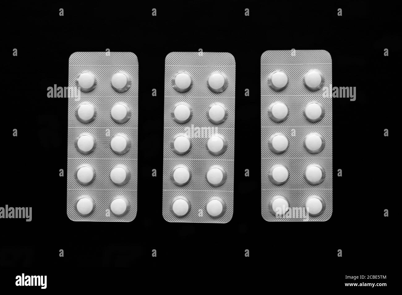 Transparent blister packs with white tablets. Isolated on black background. Top view. Horizontal shot. Stock Photo