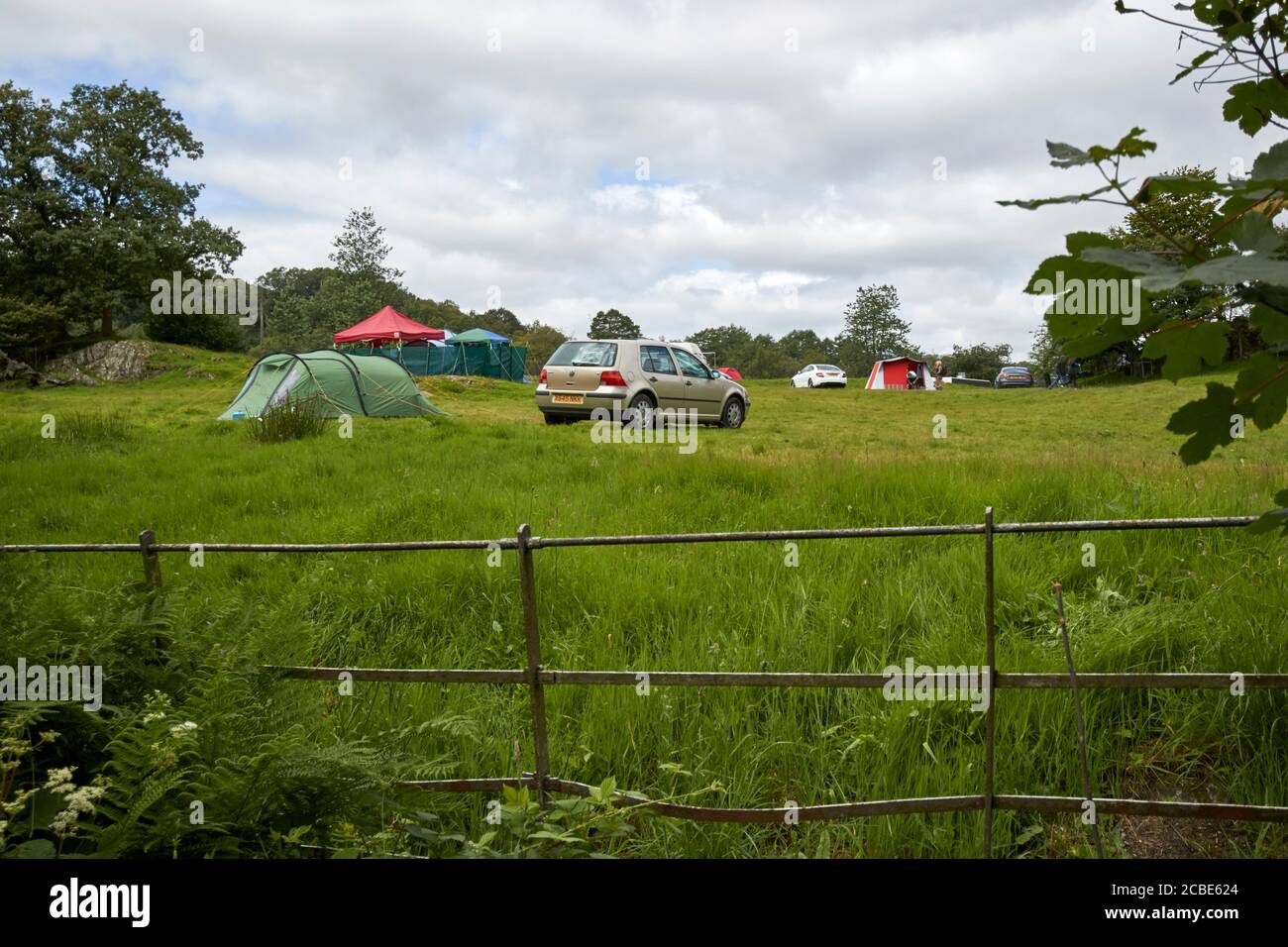 cars and tents in a farmers field campsite with people camping near loughrigg lake district cumbria england uk Stock Photo