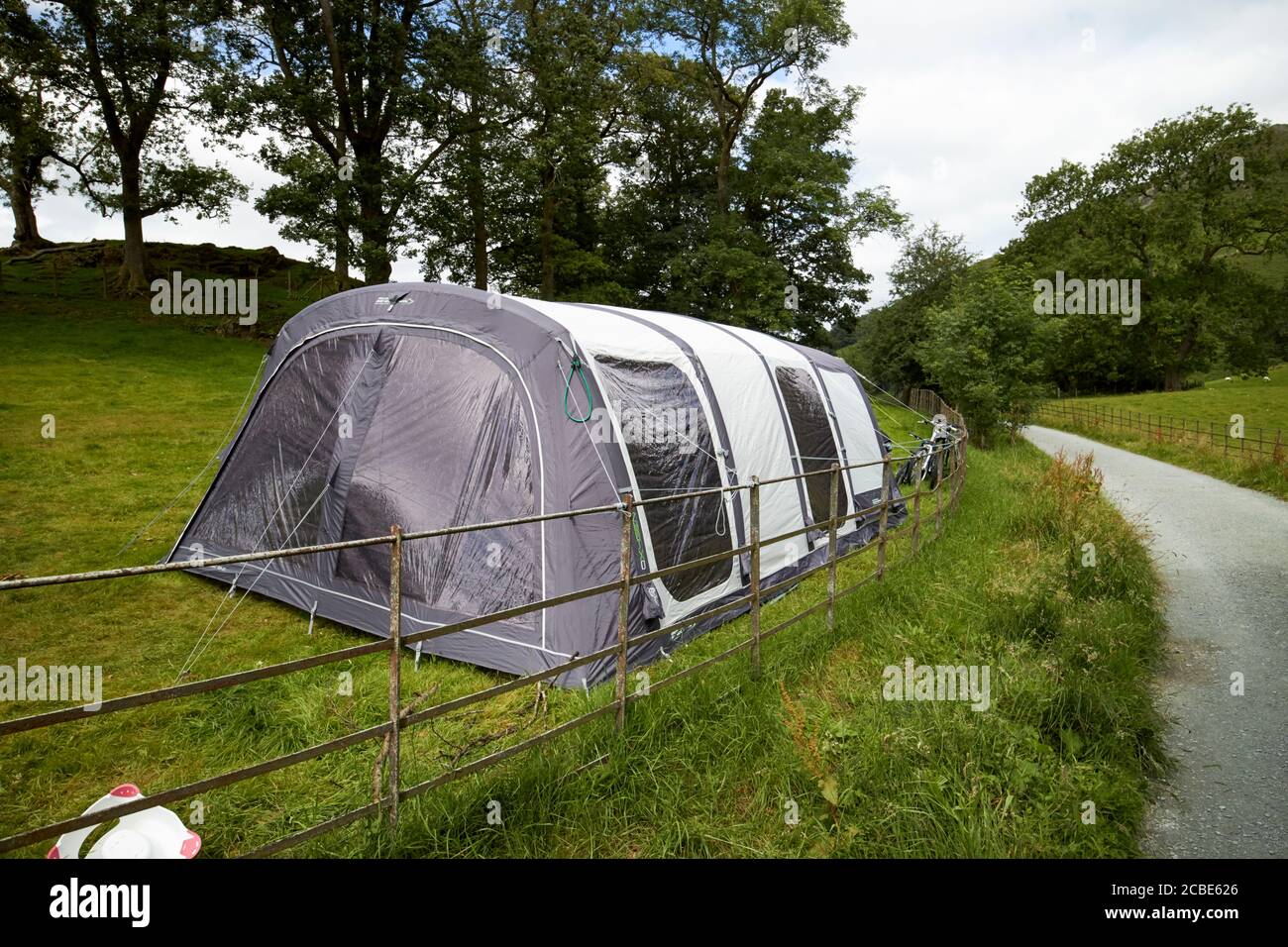 large tent in a campsite field with people camping near public footpath loughrigg lake district cumbria england uk Stock Photo