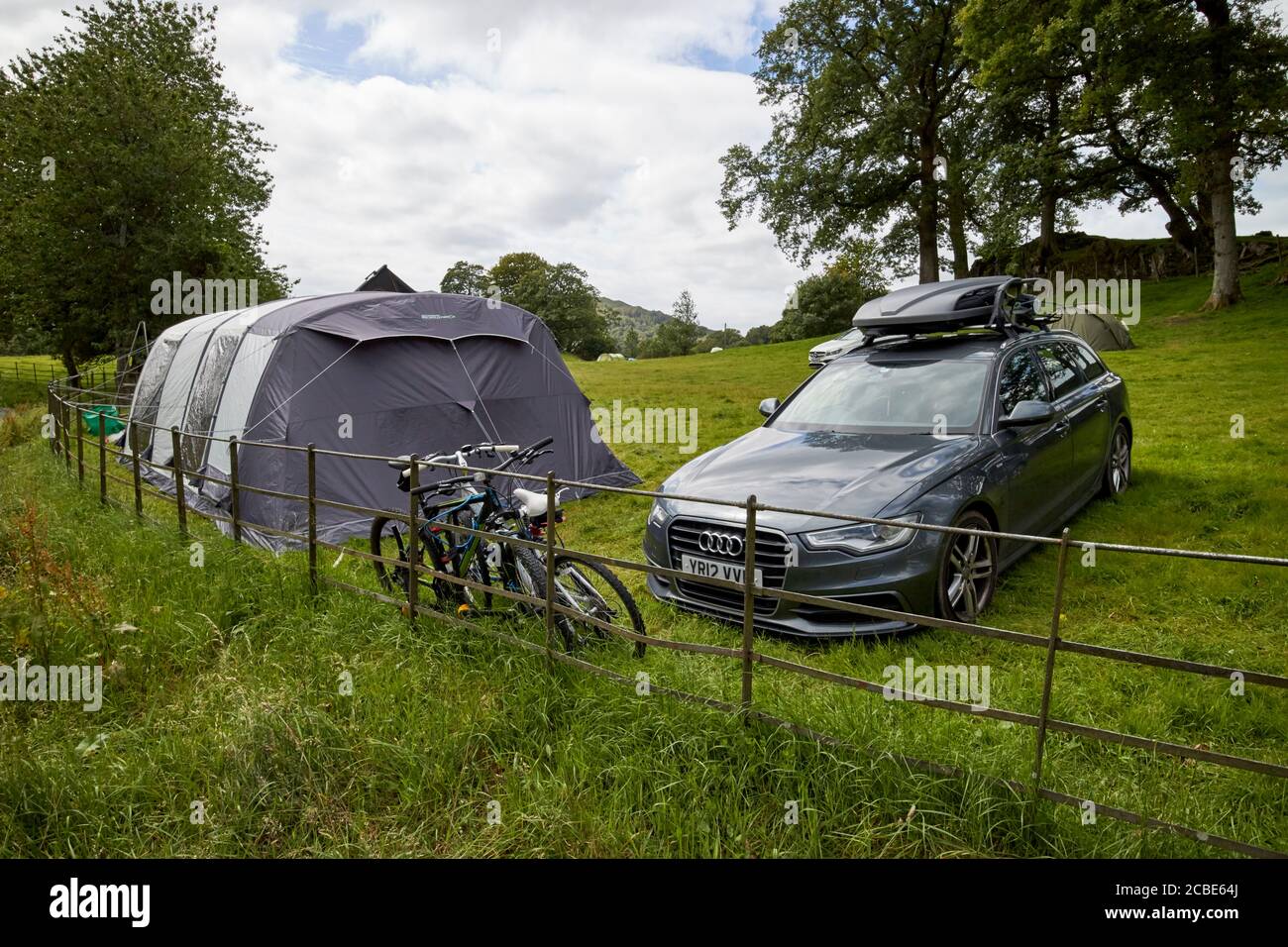 estate car with large tent in a field campsite with people camping near loughrigg lake district cumbria england uk Stock Photo