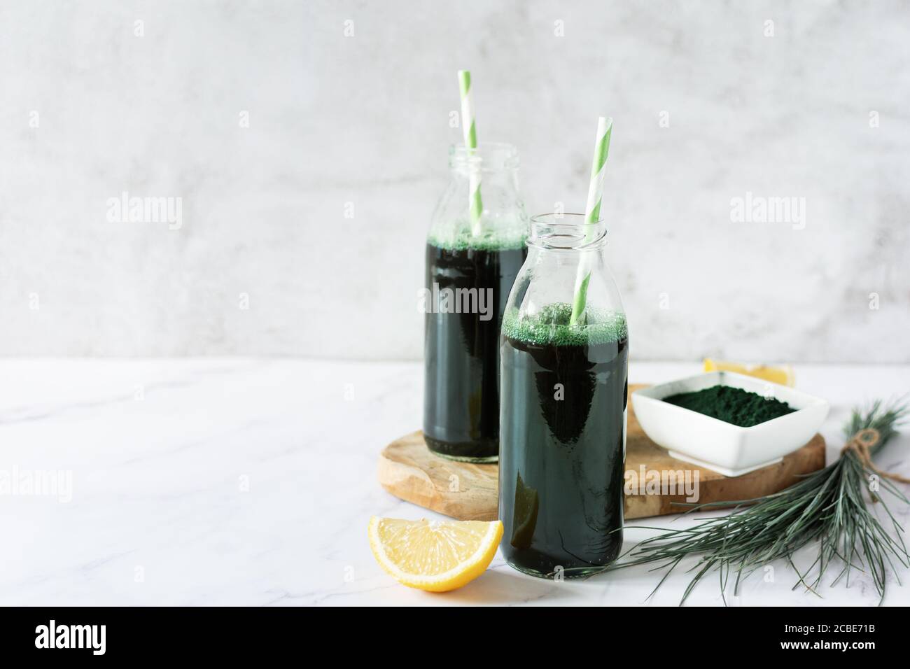 Spirulina drink with lemon and spirulina algae powder on white marble