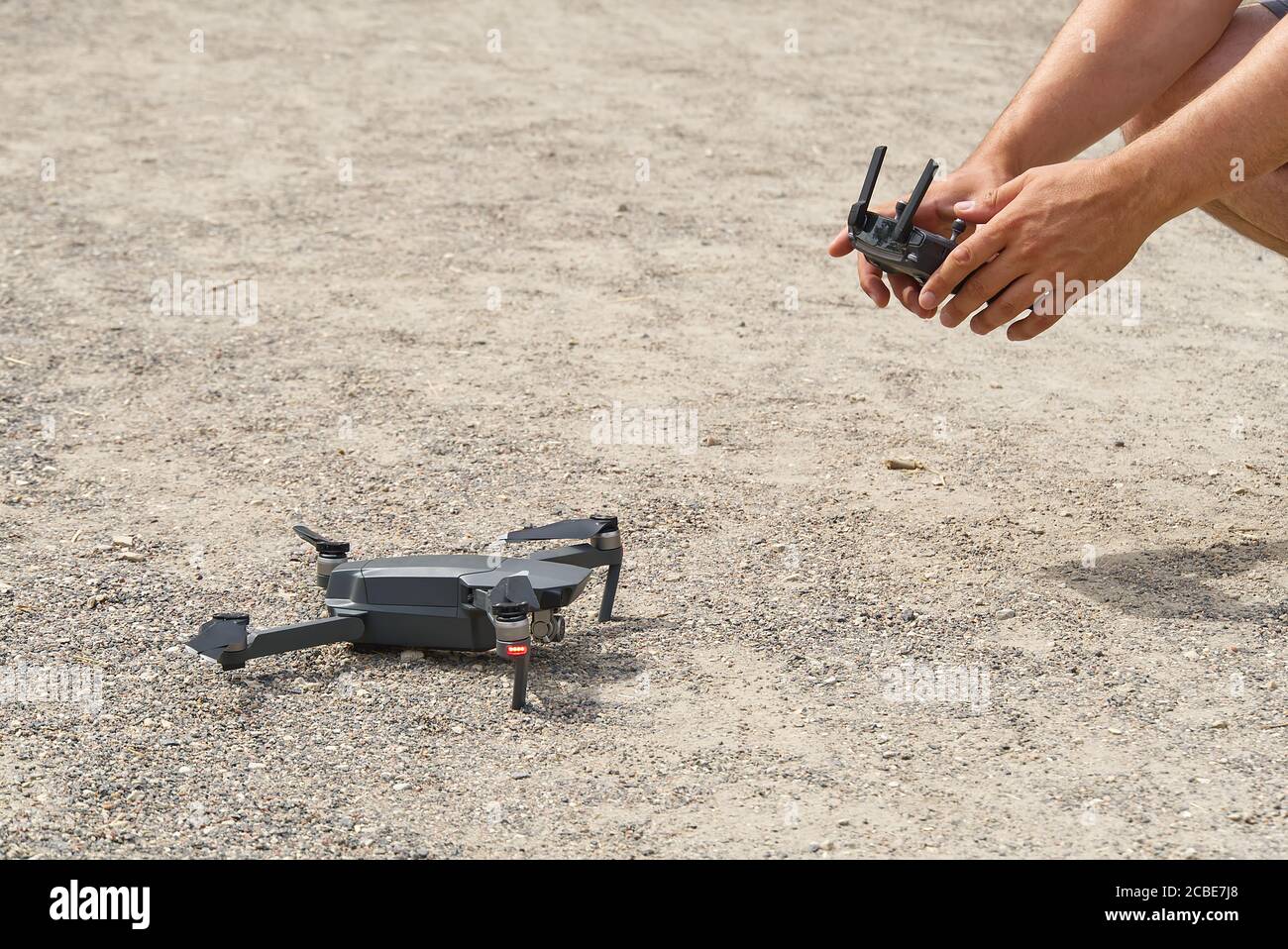 Man using remote control to operating drone assign blurred land. Stock Photo