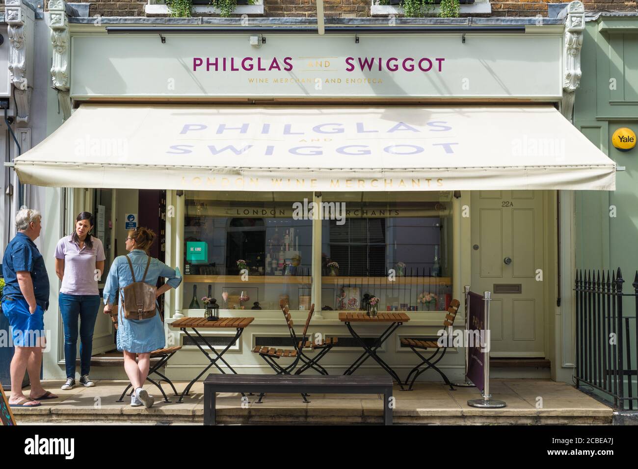 Man and two women in conversation at the doorway to Philglas and Swiggot wine merchants shop in New Quebec Street, London, England, UK Stock Photo