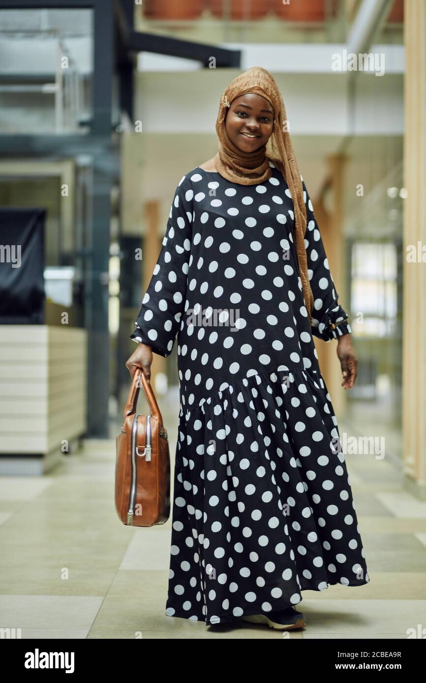 Attractive young african muslim girl wearing stylish dress, golden silk  hijab, having happy smile on her face standing with a bag in big shopping  mall Stock Photo - Alamy