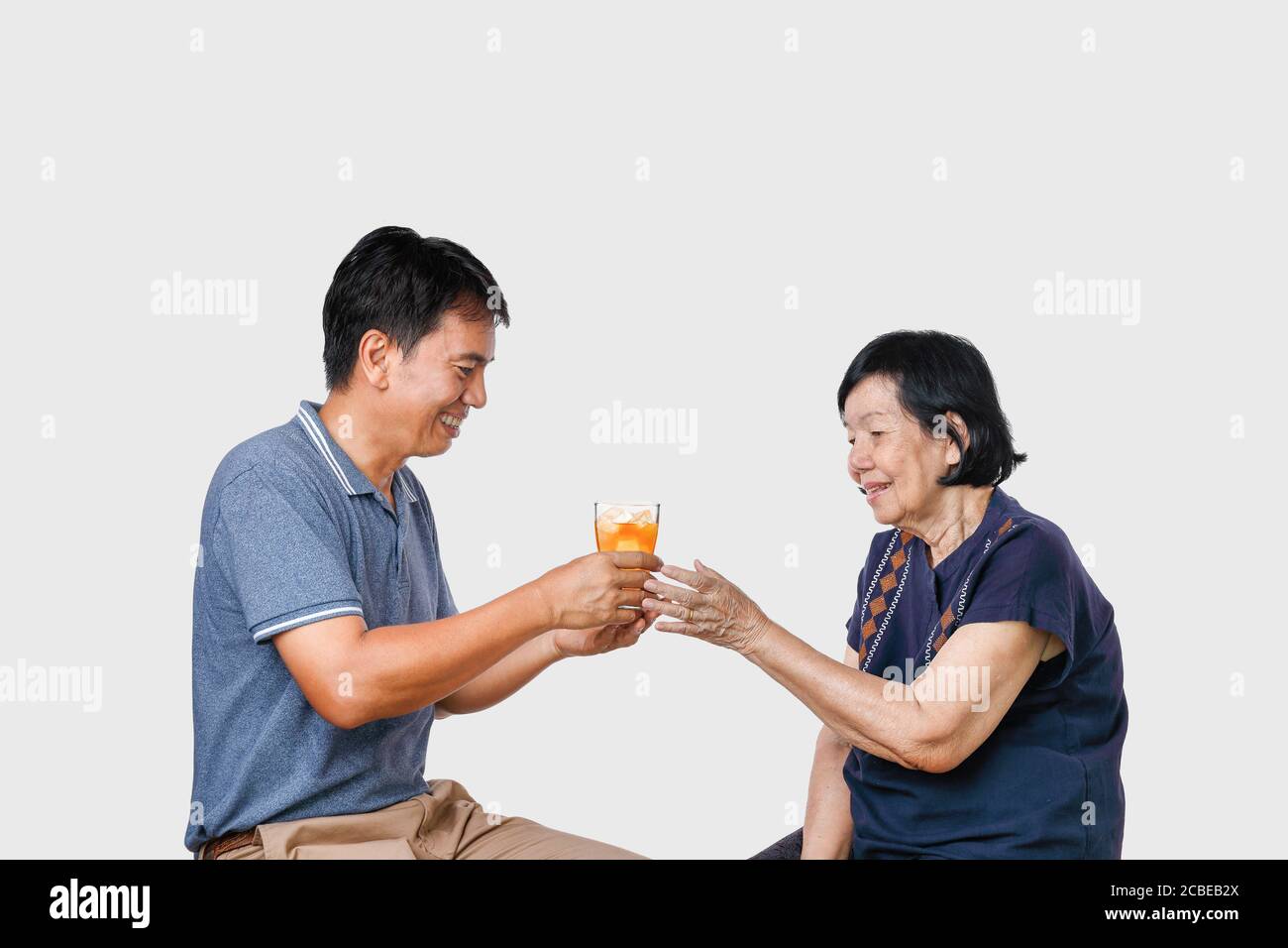 Elderly woman getting a glass of iced tea from son Stock Photo