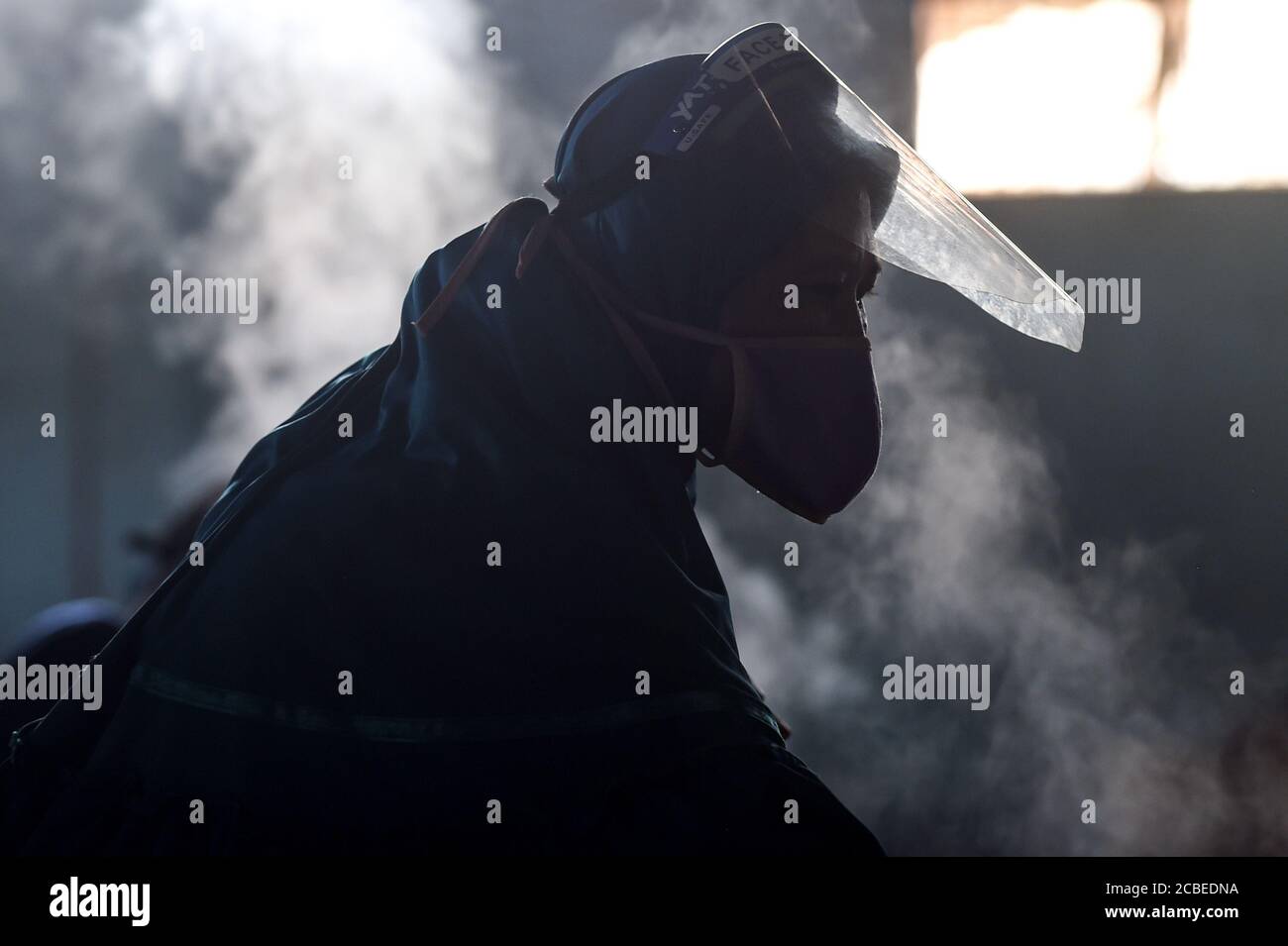 (200813) -- WEST JAVA, Aug. 13, 2020 (Xinhua) -- A worker wearinga a face mask and face shield works at a cracker factory in Depok, West Java, Indonesia, Aug. 13, 2020. Indonesia will distribute working capital assistance for 9 million small and medium enterprises (SMEs) to help them revive businesses which have been dashed by the novel coronavirus pandemic, a minister said here on Wednesday. ( Xinhua/Agung Kuncahya B.) Stock Photo