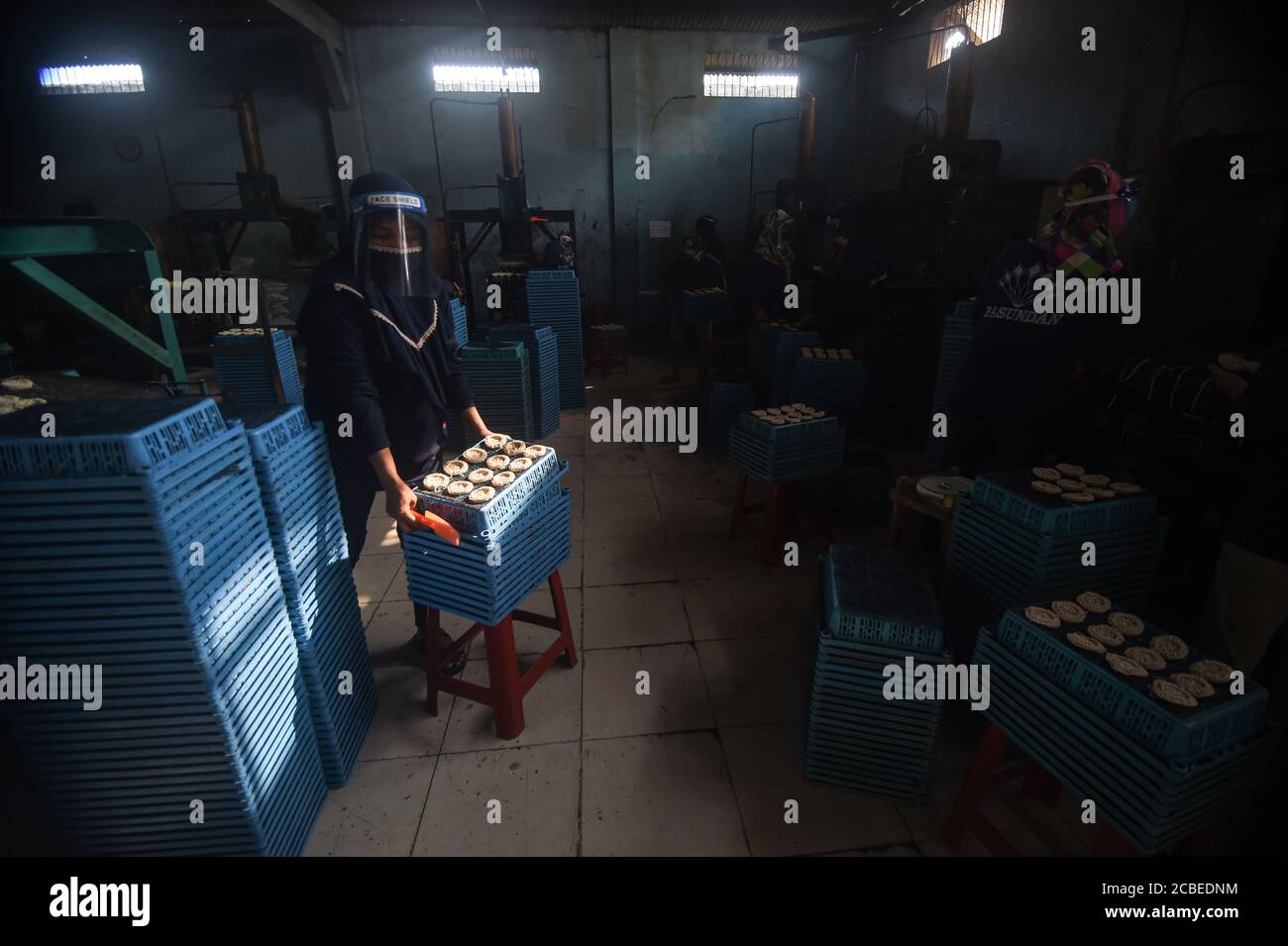 (200813) -- WEST JAVA, Aug. 13, 2020 (Xinhua) -- A worker wearing a face shield holds a tray of uncooked crackers at a cracker factory in Depok, West Java, Indonesia, Aug. 13, 2020. Indonesia will distribute working capital assistance for 9 million small and medium enterprises (SMEs) to help them revive businesses which have been dashed by the novel coronavirus pandemic, a minister said here on Wednesday. ( Xinhua/Agung Kuncahya B.) Stock Photo