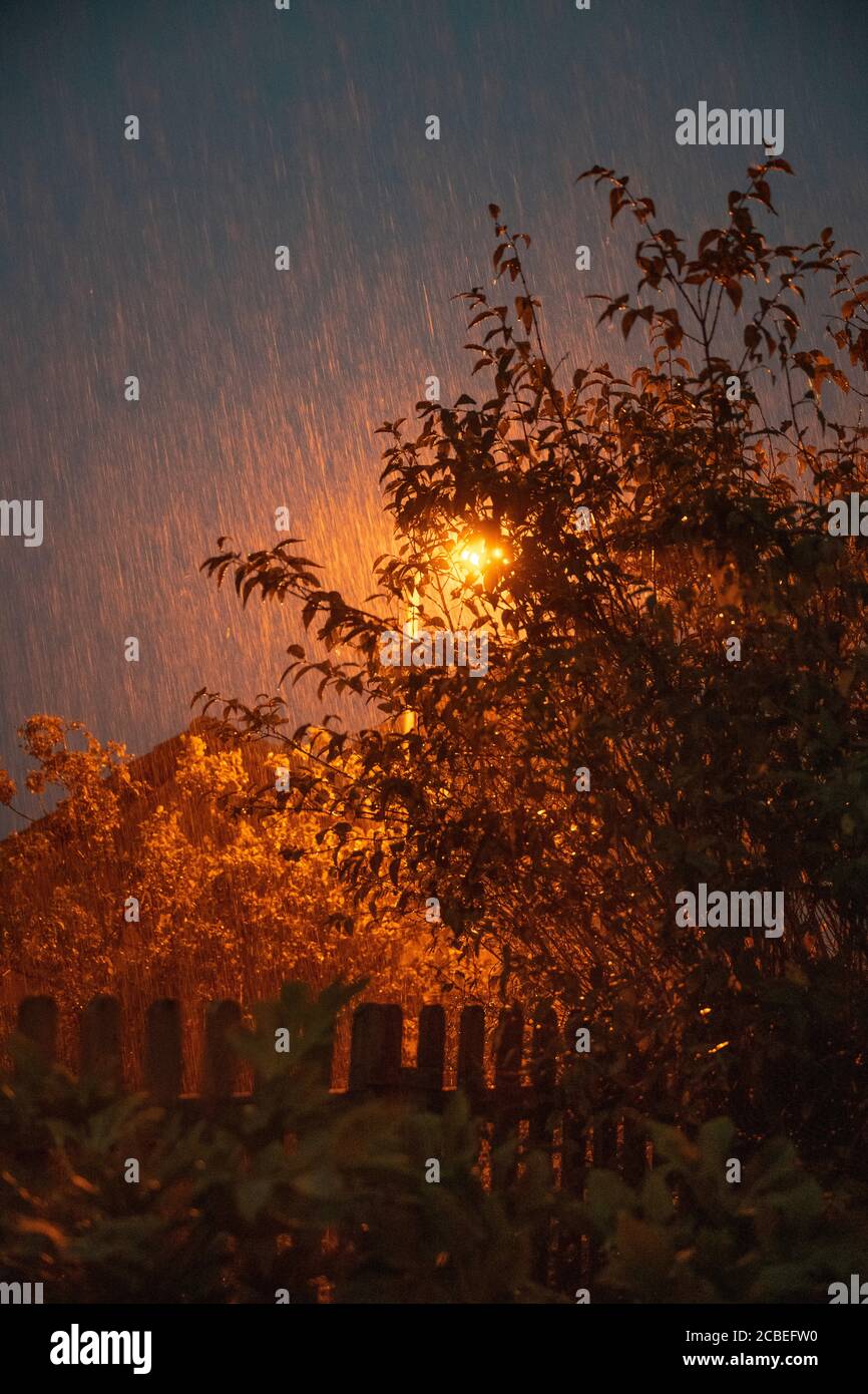 Torrential rain at night lit by a street lamp during a summer storm in the UK. Stock Photo
