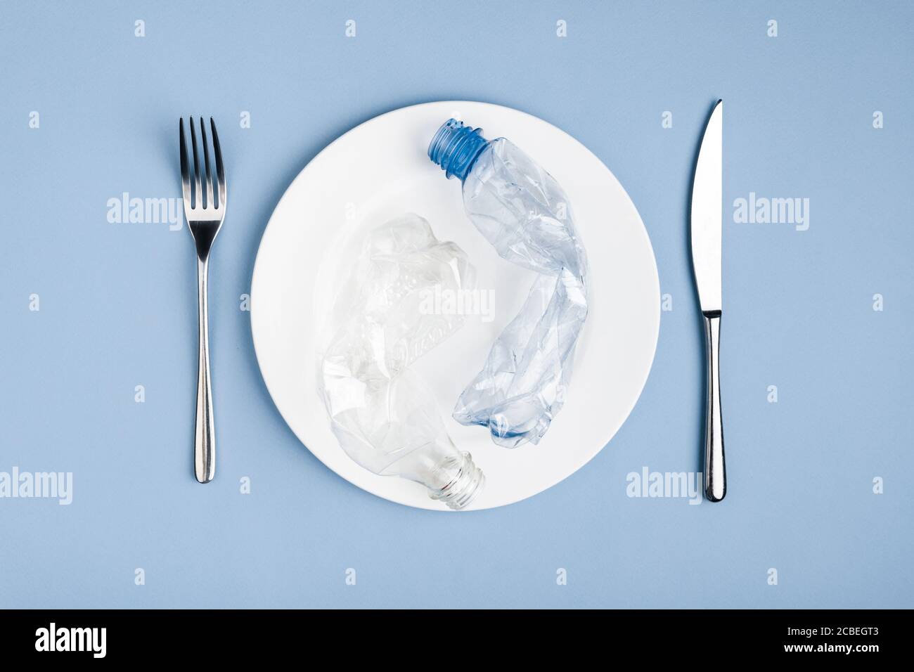 Top view of plastic waste garbage in the white plate, knife and fork Stock Photo