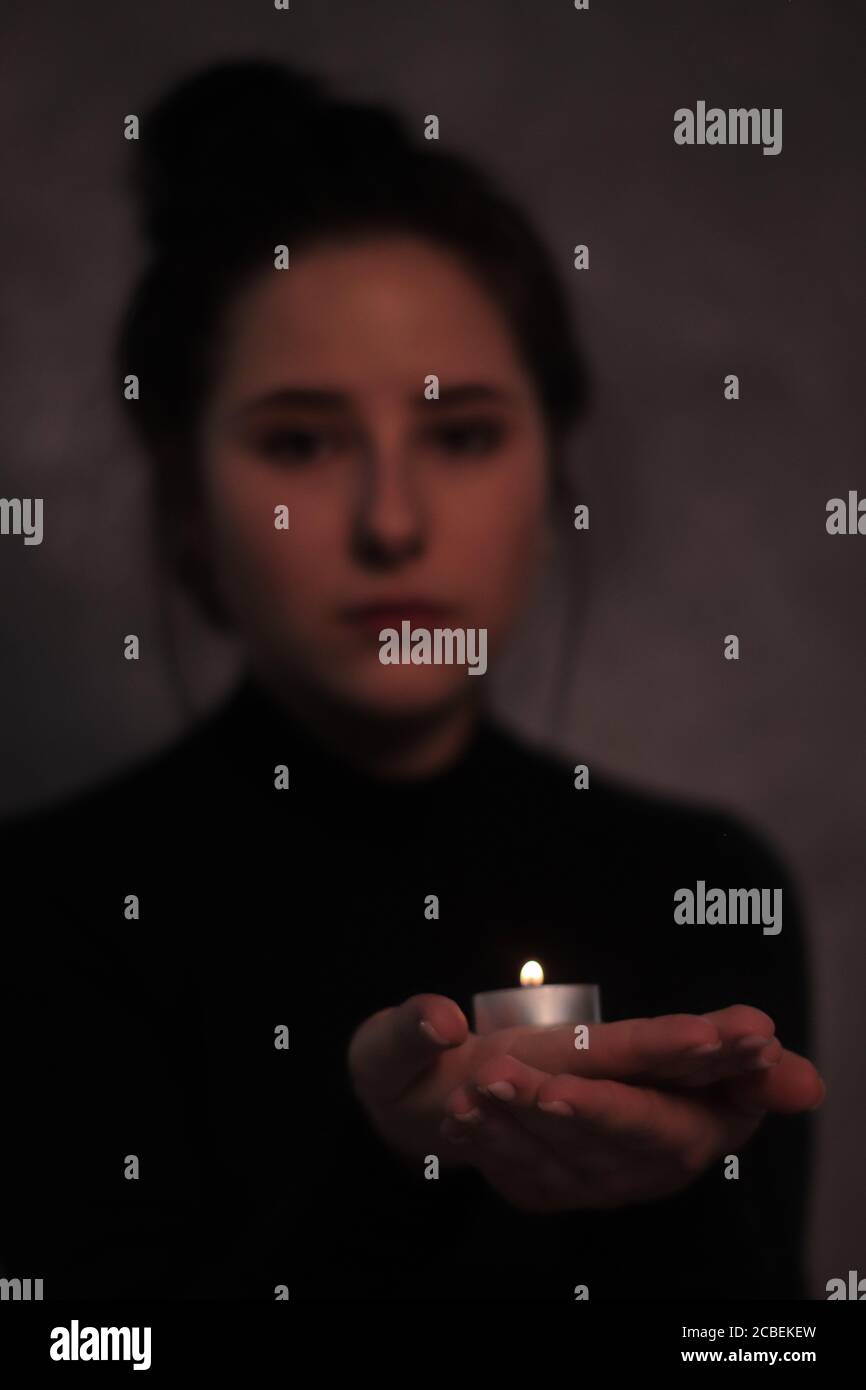 sad brunette girl almost burst into tears holding candle Stock Photo sad brunette girl almost burst into tears holding candle Stock Photo