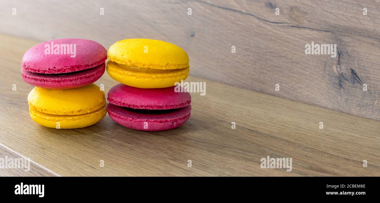 lemon and strawberry macarons stacked on wooden table, panorama Stock Photo