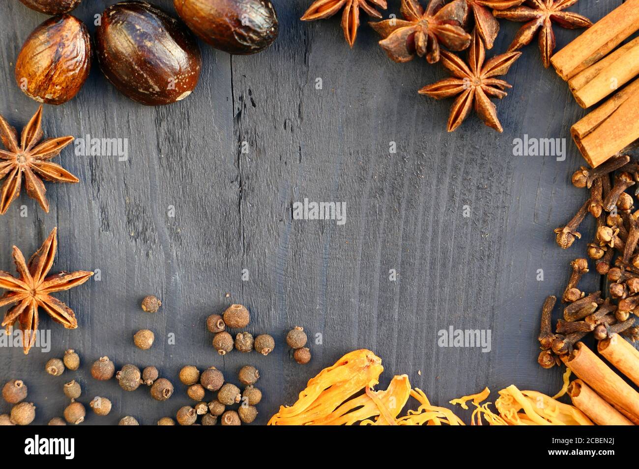 Border of spices on wooden background. Cinnamon, nutmeg, cloves