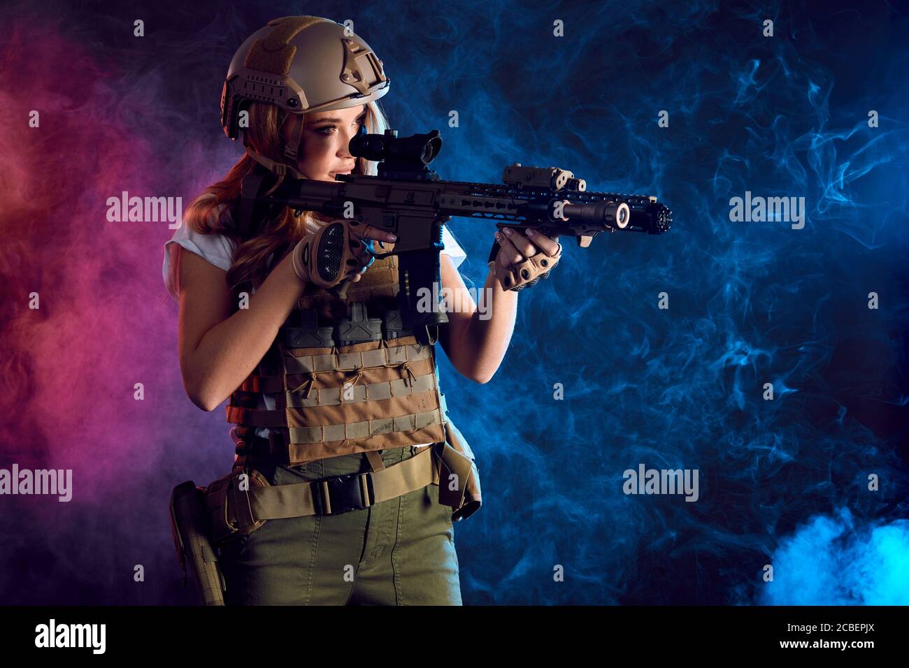 woman sniper in body armour with SVD sniper rifle. Female serving in Army, soldier with machine gun. Shot in studio. Smoky dark background imitating e Stock Photo