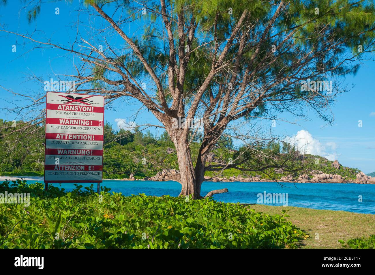 Warning sign post of strong current at the beach of Anse Cocos, La Digue island, Seychelles Stock Photo