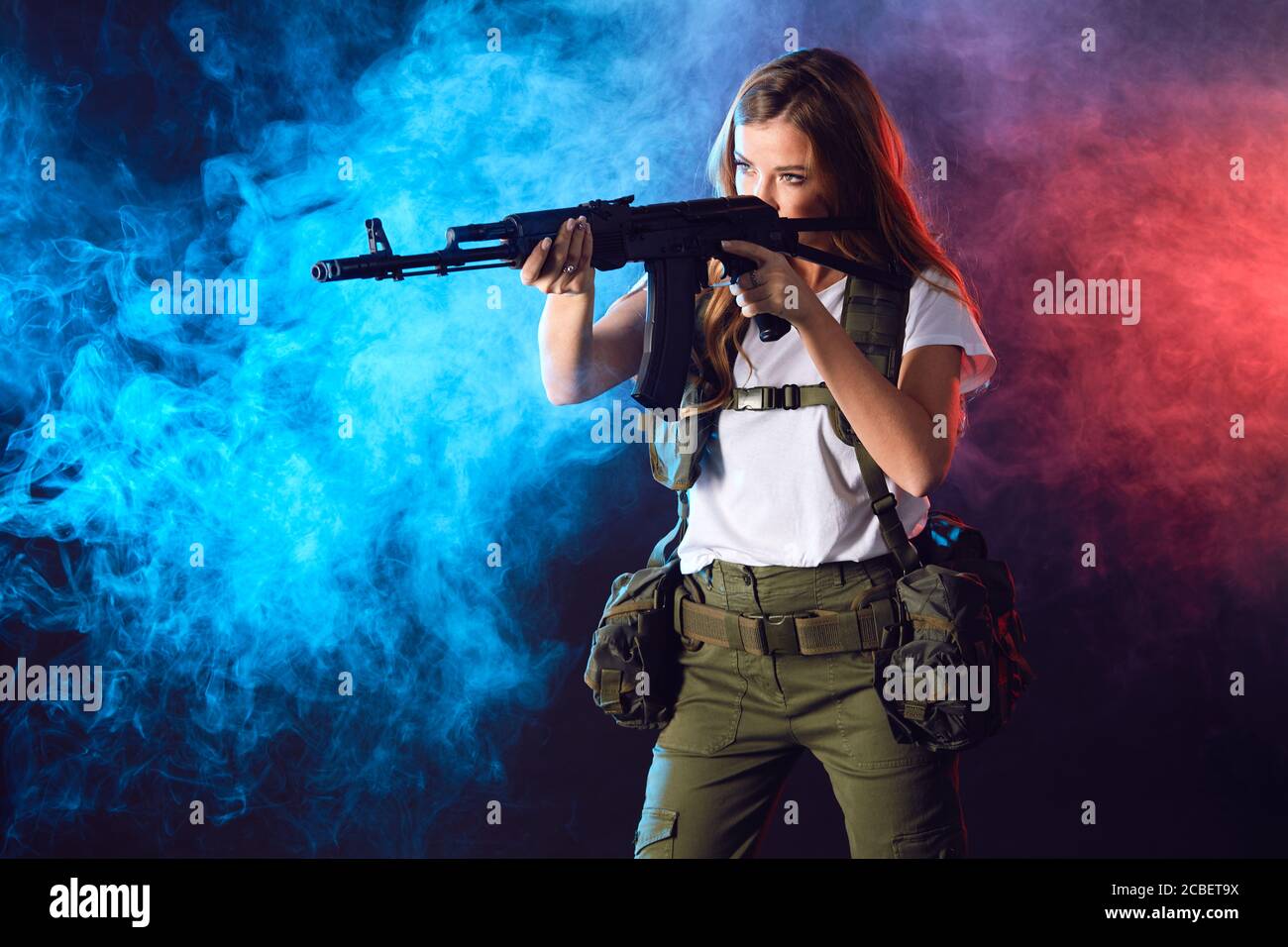 woman sniper with SVD sniper rifle. Female in US Army soldier with rifle. Shot in studio over smoky red and blue dual color baclground imitating explo Stock Photo