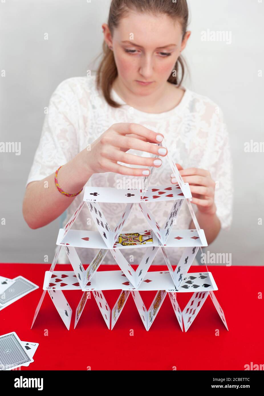 A teenage girl builds a house of playing cards Stock Photo