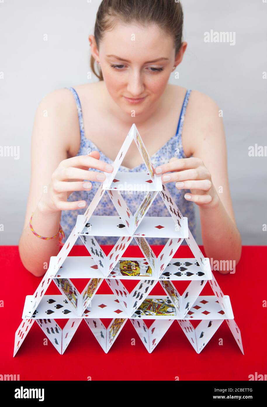 A teenage girl building a house of cards Stock Photo