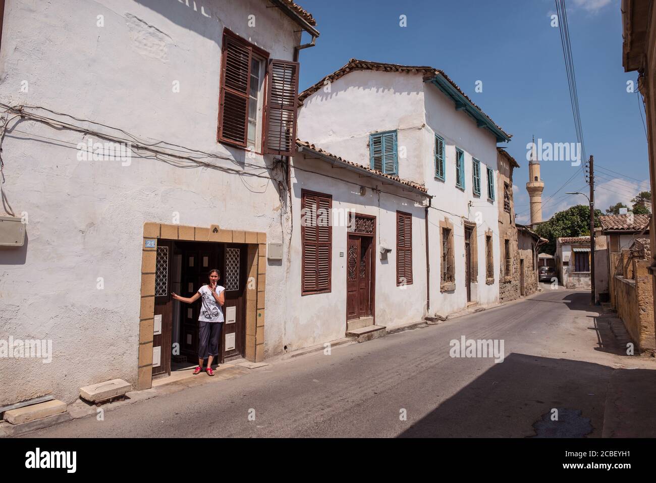 Nicosia / Northern Cyprus - August 15, 2019: Ethnic Turkish woman leaning out of her house with a mosque in the background in the part of Nicosia that belongs to North Cyprus Stock Photo