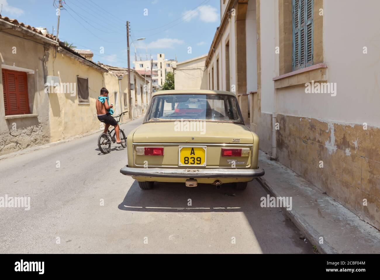 Nicosia / Northern Cyprus - August 15, 2019: boy riding a bicycle next to old vehicle on the Turkish side of Nicosia belonging to North Cyprus Stock Photo