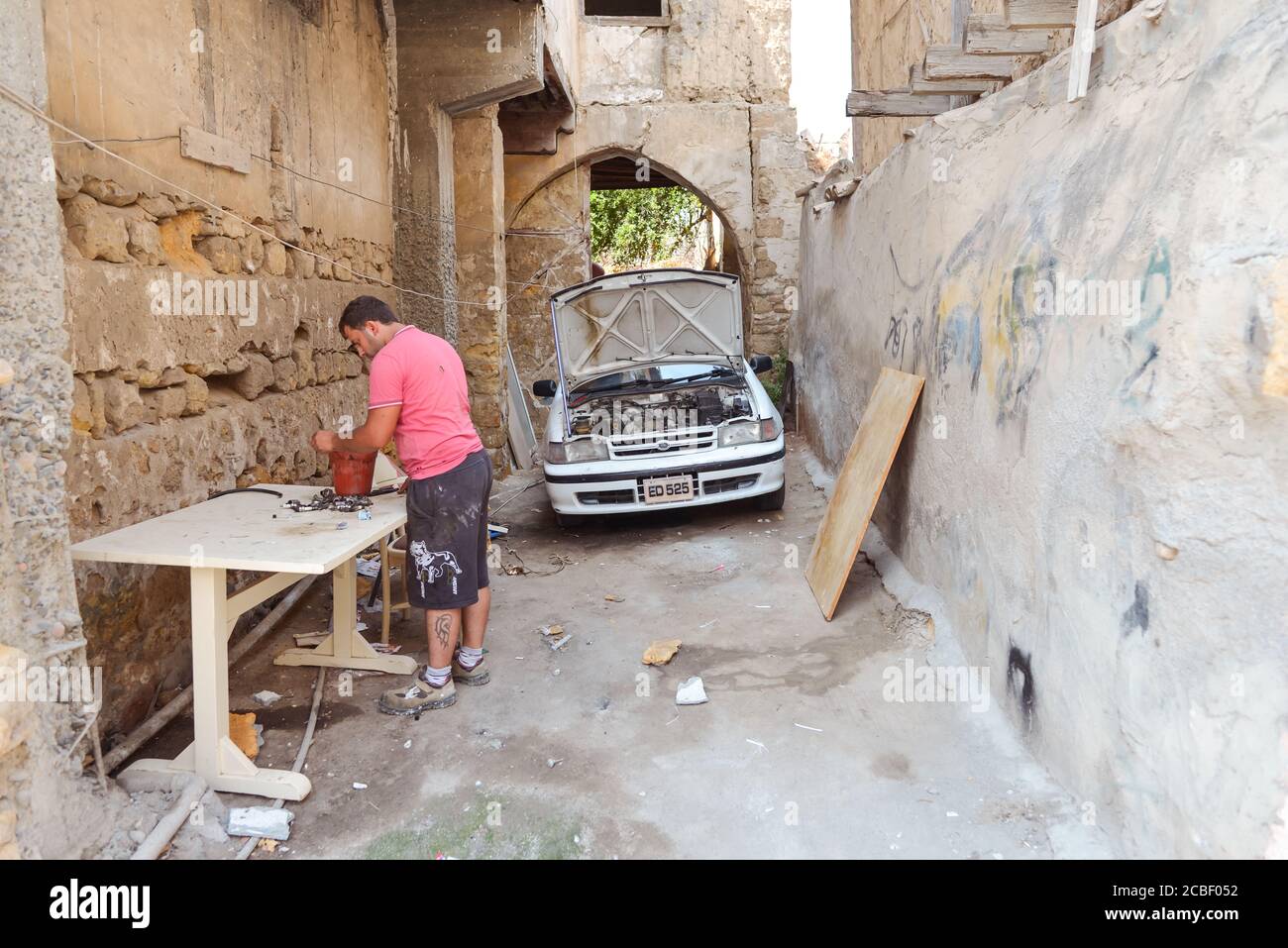 Nicosia / Northern Cyprus - August 15, 2019: man repairing car in alley on Turkish side of Nicosia belonging to North Cyprus Stock Photo