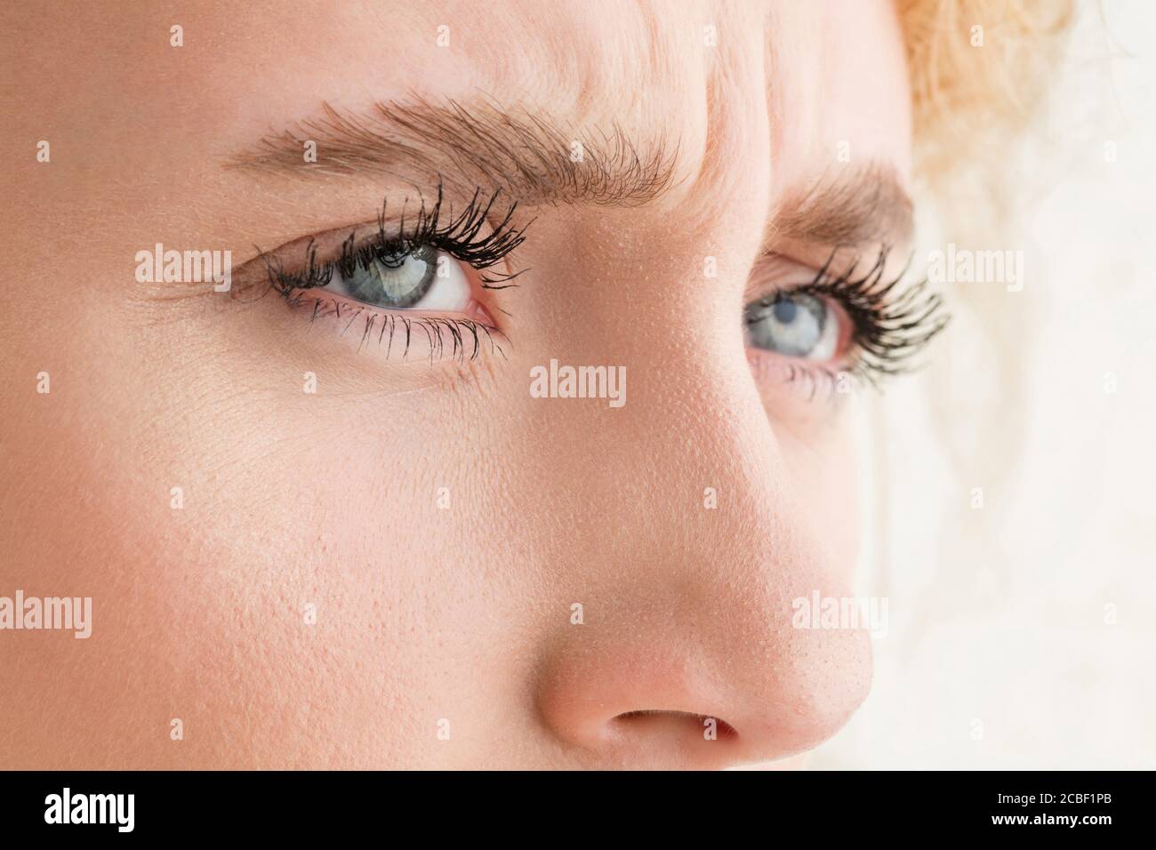 Squinting. Close up of face of beautiful caucasian young woman, focus on  eyes. Human emotions, facial expression, cosmetology, body and skin care  concept. Well kept cheeks, narutal make up. Wellbeing Stock Photo -