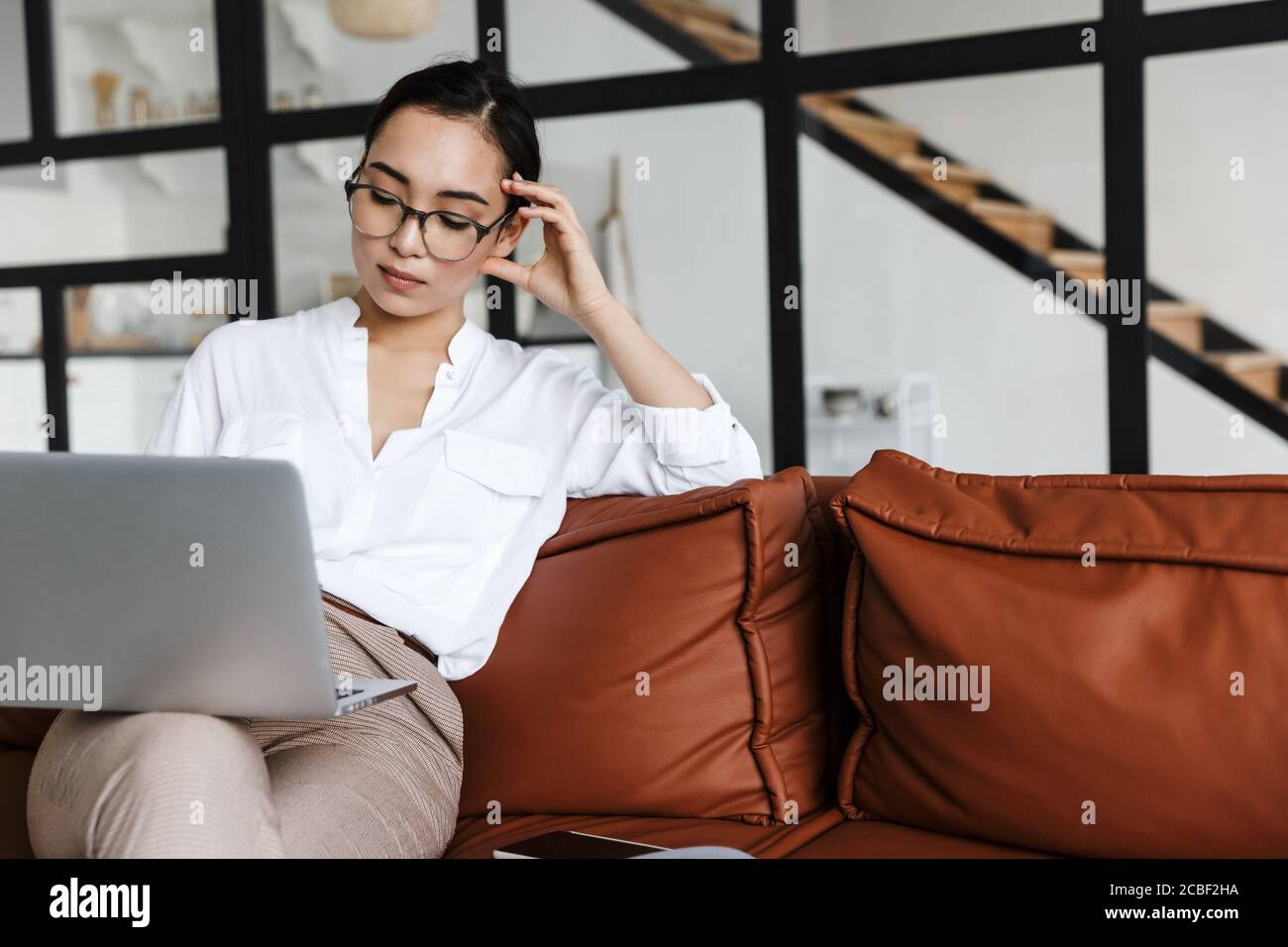 Attractive young asian business woman relaxing on a leather couch at ...