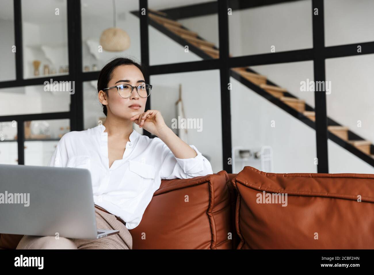 Attractive young asian business woman relaxing on a leather couch at ...